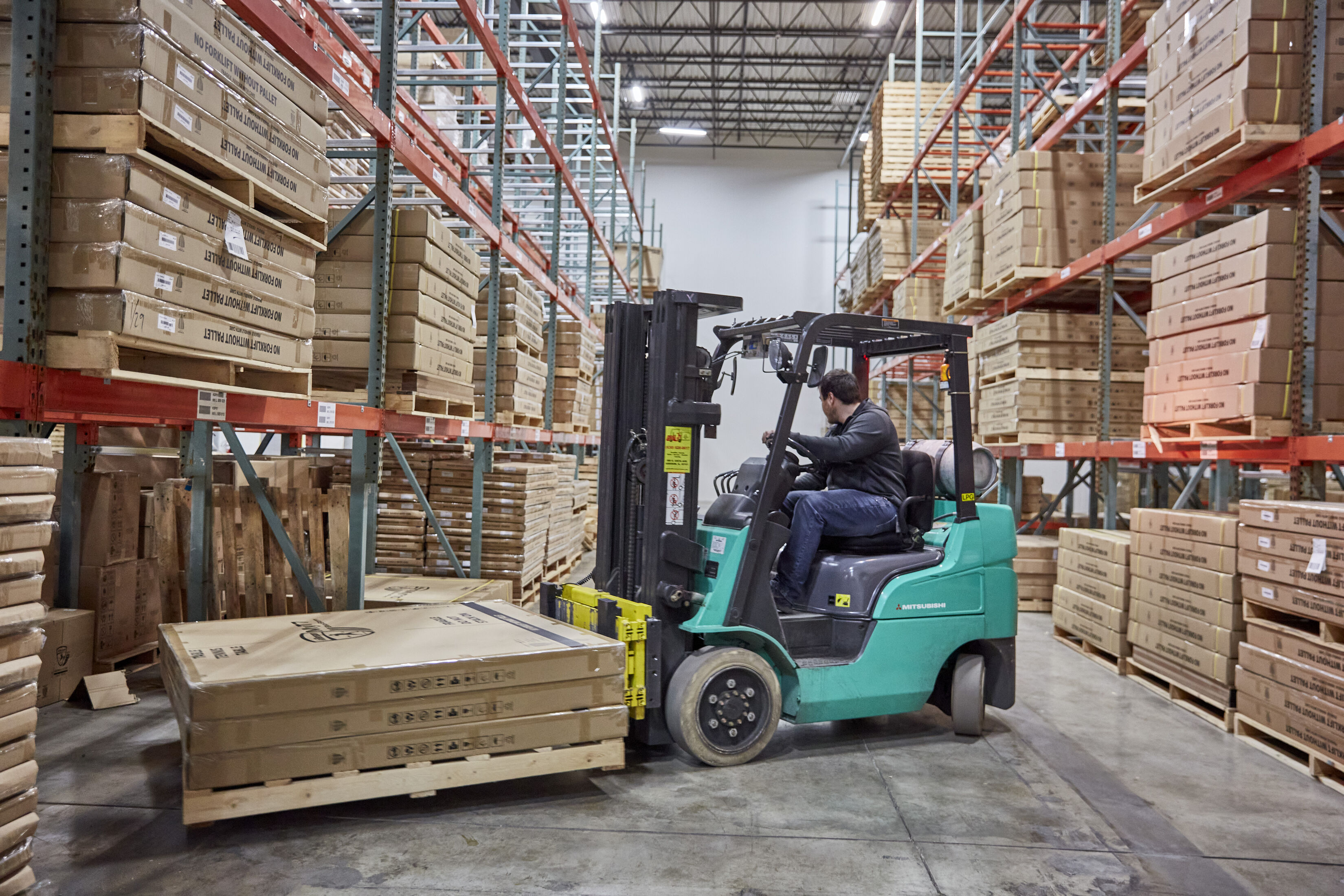 Warehouse employee moving pallets with a forklift